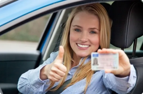 Щаслива випускниця автошколи Драйвер+ з водійським посвідченням — показує палець вгору