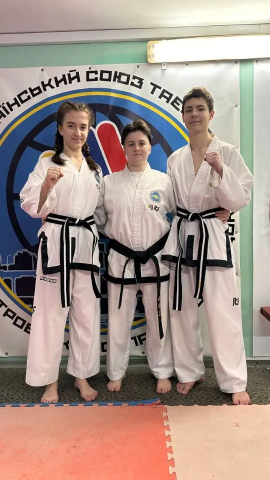 Троє підлітків з чорними поясами у бойових стійках