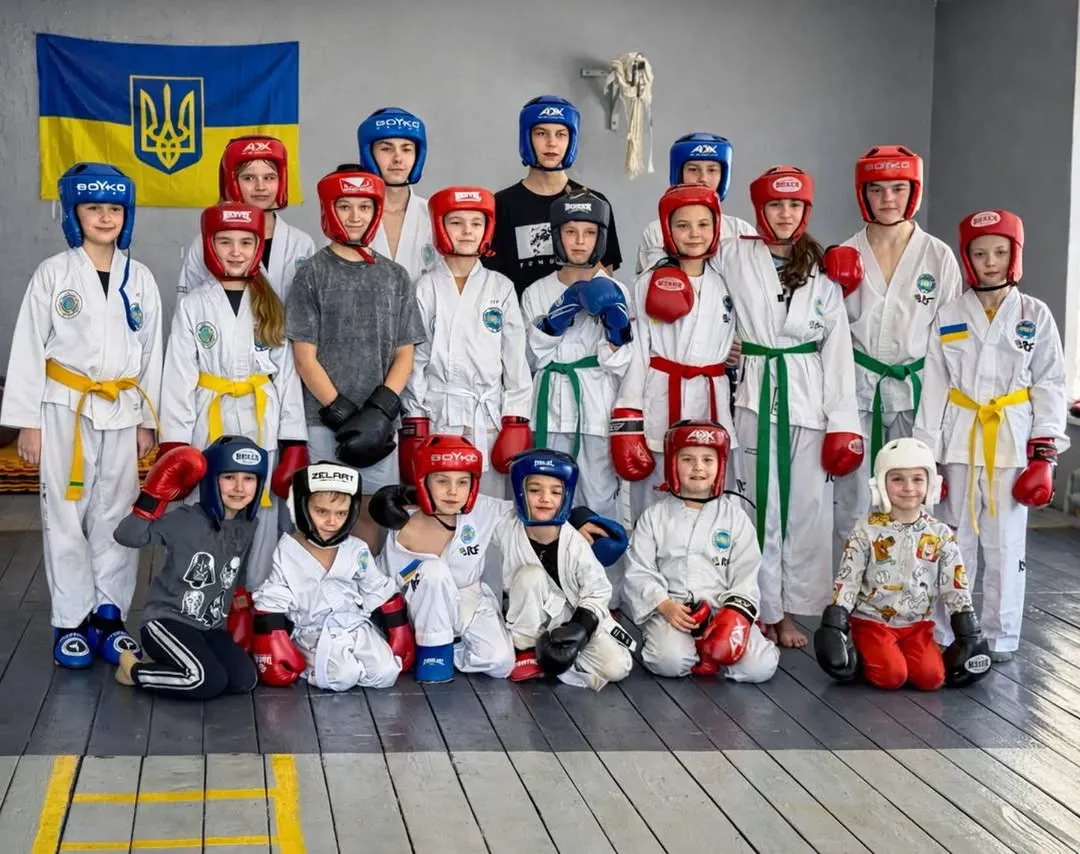 Група дітей у добоках з кольоровими поясами та захисних шоломах на тренуванні в Liberty Club