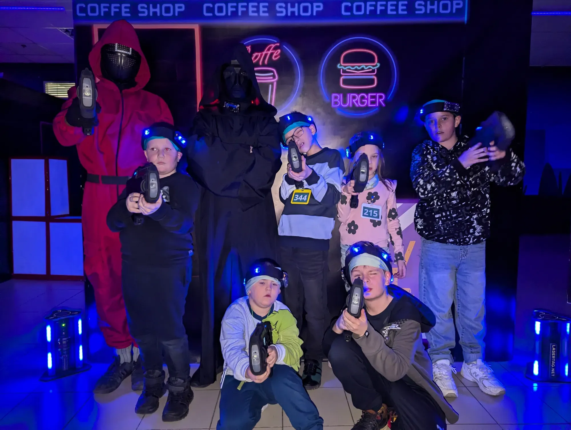 Група молодих людей у лазертаг-обладнанні в футуристичному інтер'єрі