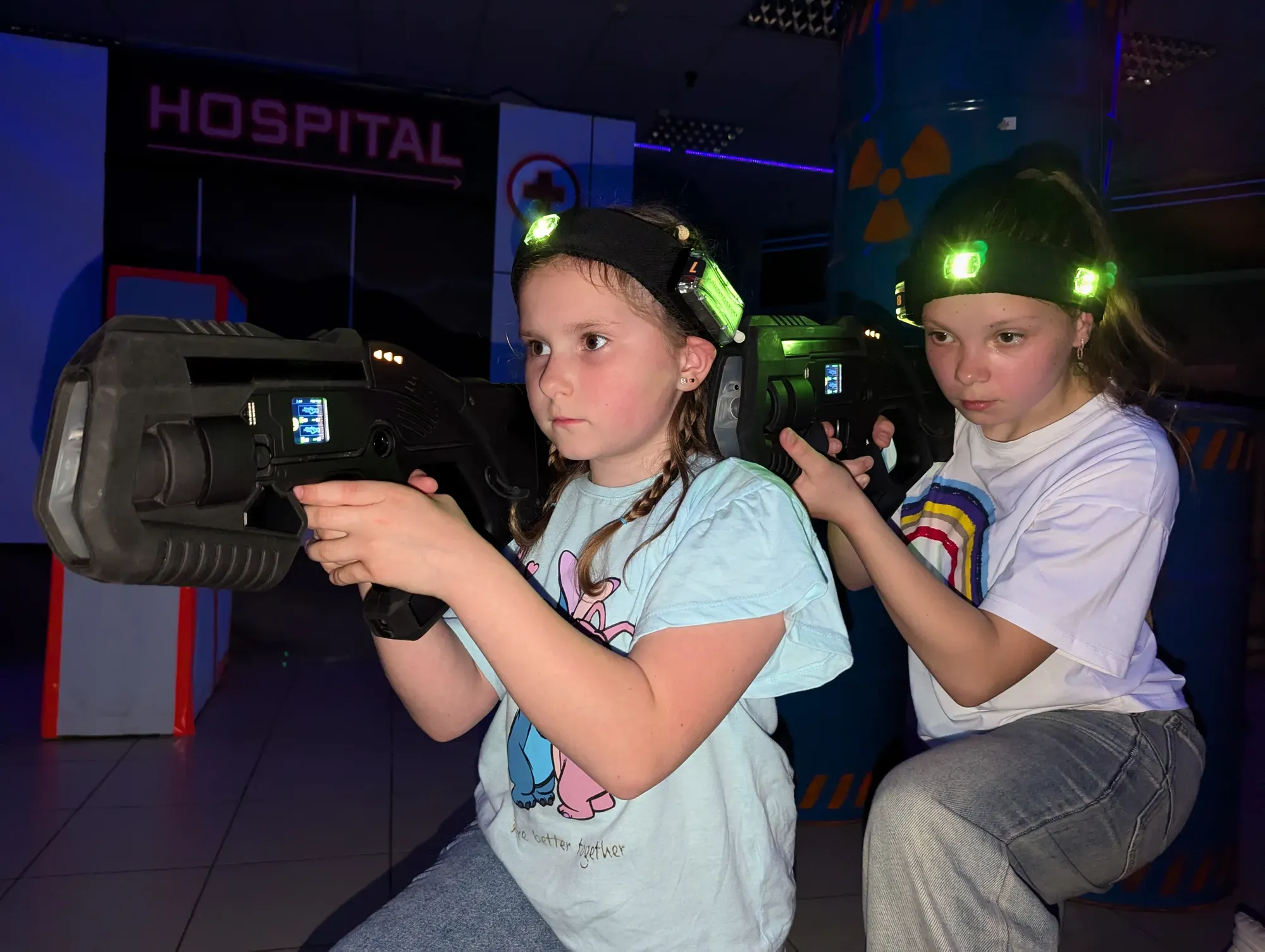 Дві дівчини-підлітки з посмішками грають у лазертаг в клубі Авалон