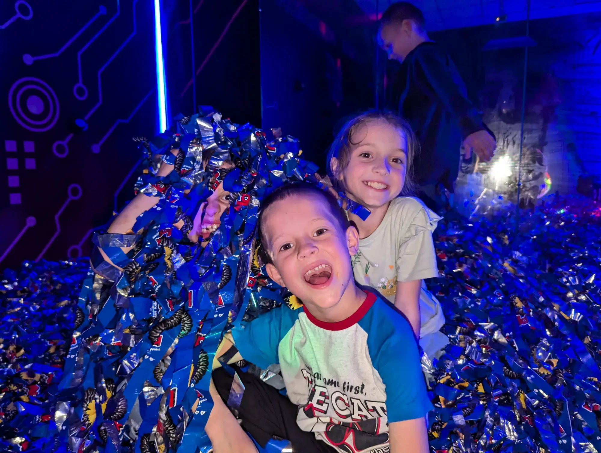 Двоє радісних дітей серед блискучих конфеті з неоновим освітленням