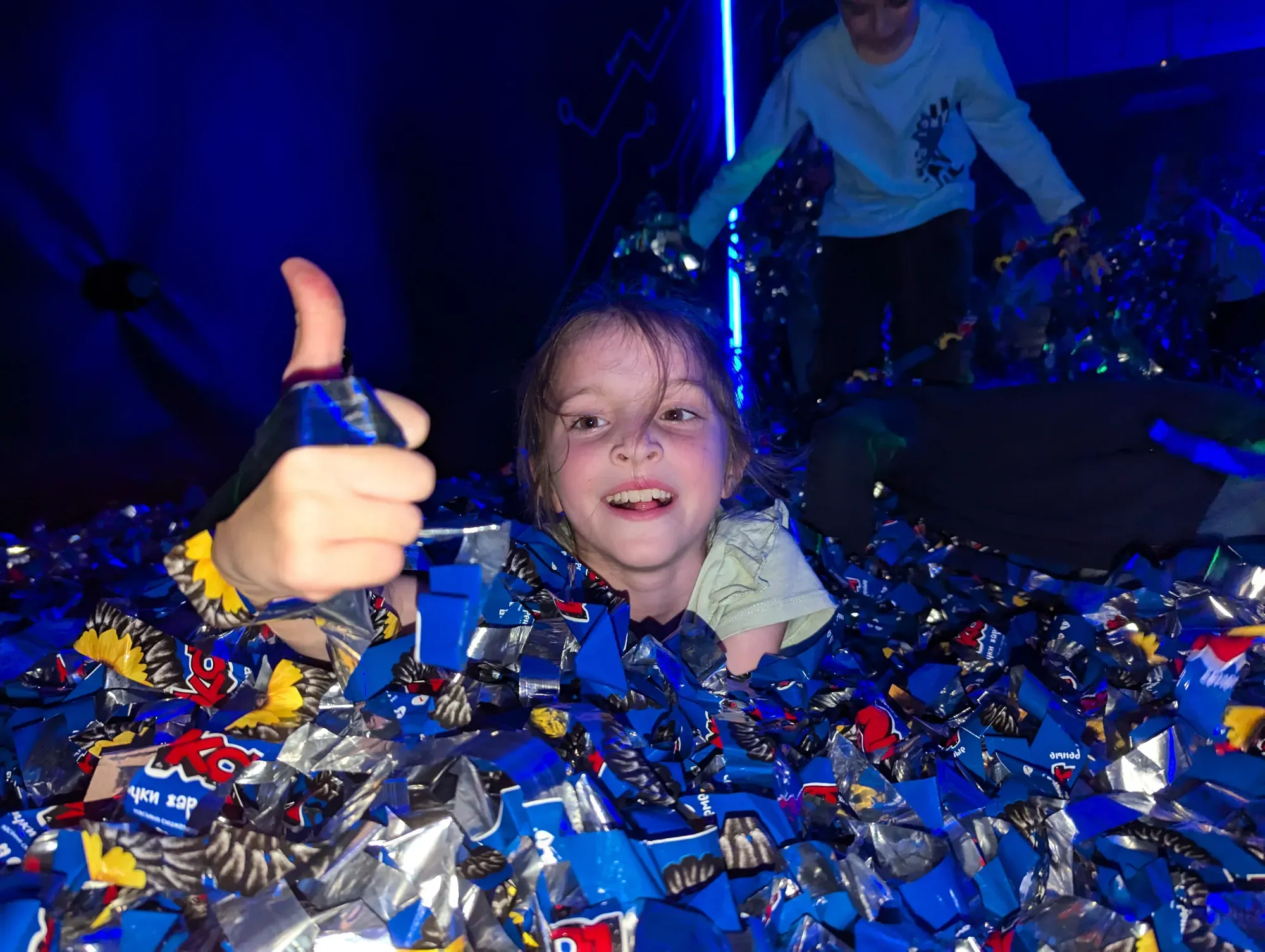 Щаслива дитина показує палець вгору серед яскравих конфеті в клубі Авалон