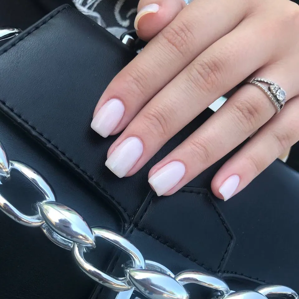 Нюдовий манікюр на фоні шкіряної сумки з ланцюгом