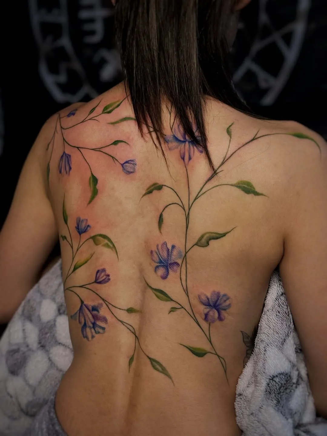 Квіткове тату на спині — ніжна композиція з фіолетовими квітами
